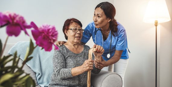 Caregiver, carer hand holding elder hand woman in hospice care. Philanthropy kindness to disabled concept.Public Service Recognition Week. Attentive young doctor talks with female patient